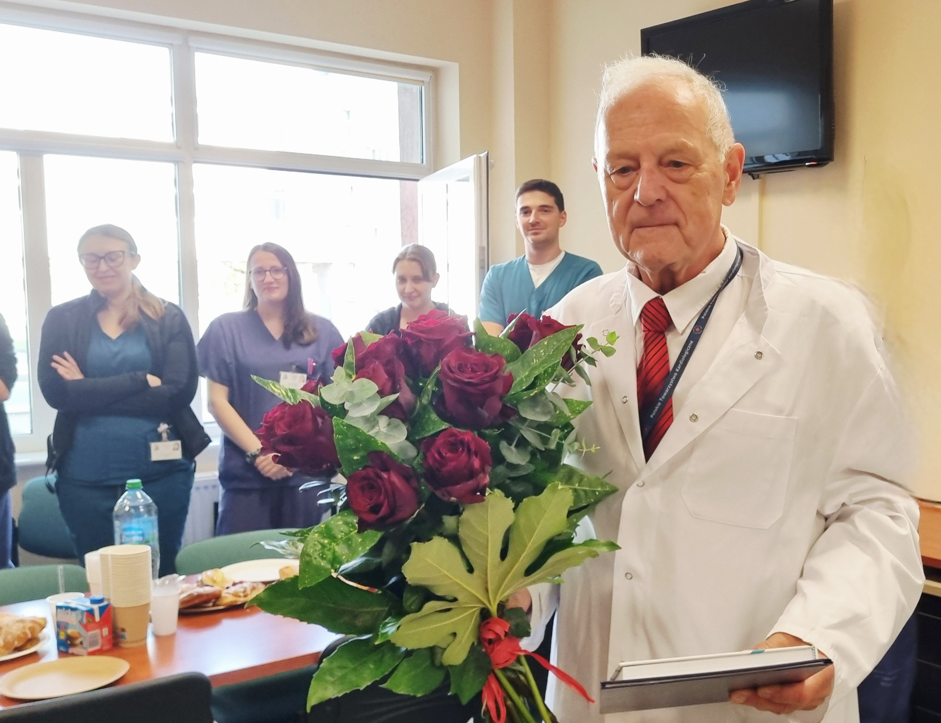 Mężczyzna w białym fartuchu, lekarz, z kwiatami w rękach