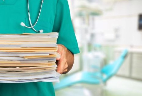 Grafika przedstawiająca personel medyczny niosący papierową dokumentację medyczną
