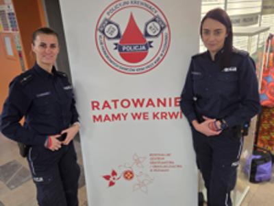Policjantki na tle plakatu klubu krwiodawców 