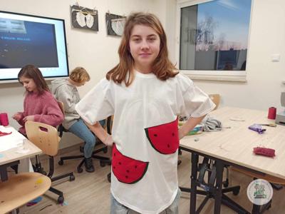 Uczestniczka zajęć prezentuje t-shirt udekorowany podczas zajęć.