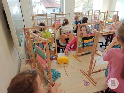 Dzieci podczas zajęć w pracowni rękodzielniczej. Tkają na krosnach tkackich.
