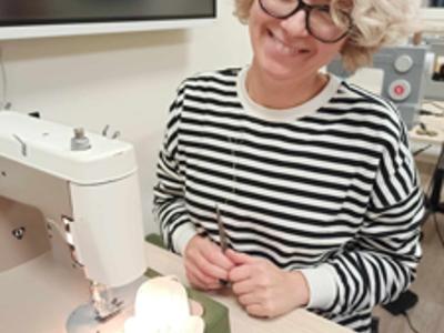 Uczestniczka podczas szycia w pracowni krawieckiej.
