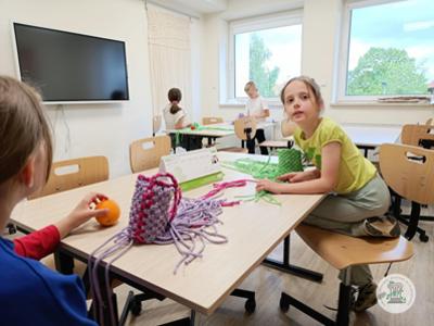 Dzieci podczas zajęć z makramą w pracowni rękodzielniczej.