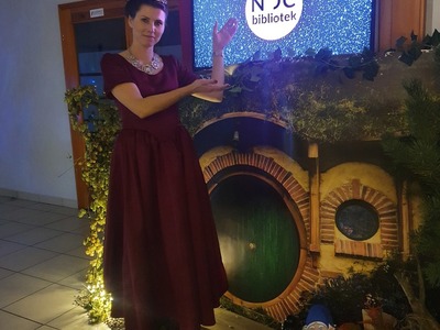 aranżacja baśniowej krainy, kobieta przebrana za księżniczkę przed drzwiami do domu hobbita