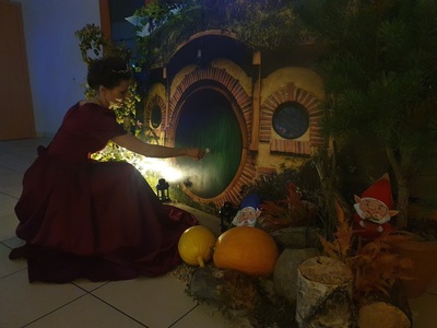 aranżacja baśniowej krainy, kobieta przebrana za księżniczkę przed drzwiami do domu hobbita