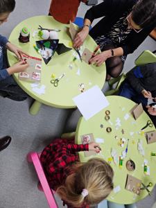 Osoby wykonujące rękodzieło w postaci kartek siedzące przy stolikach