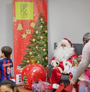Mikołaj siedzący na fotelu obok kręcą się dzieci