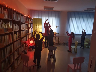kobieta oraz dzieci w sali bibliotecznej, naśladujące ruchy kota