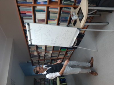 sala biblioteczna, regały z książkami, mężczyzna przy tablicy Flipchart