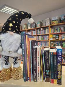 książki stojące grzbietami, obok krasnal