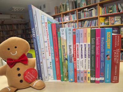 książki stojące grzbietami, obok maskotka ciastek