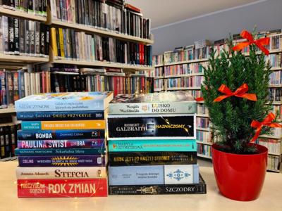 książki leżące grzbietami, obok drzewko w czerwonej donicy