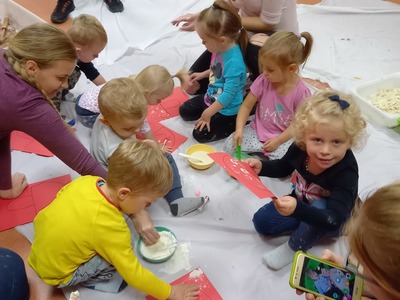 Dzieci siedzące na podłodze i malujące patyczkami do uszu