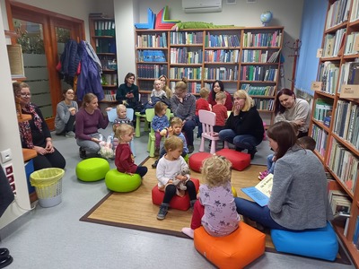 Grupa dzieci oraz rodziców siedzących w sali