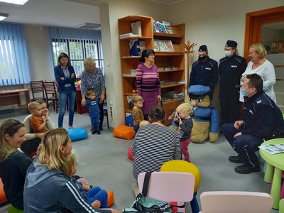 Grupa dzieci siedząca w sali twarzami skierowanymi w stronę policjanta i dwóch policjantek