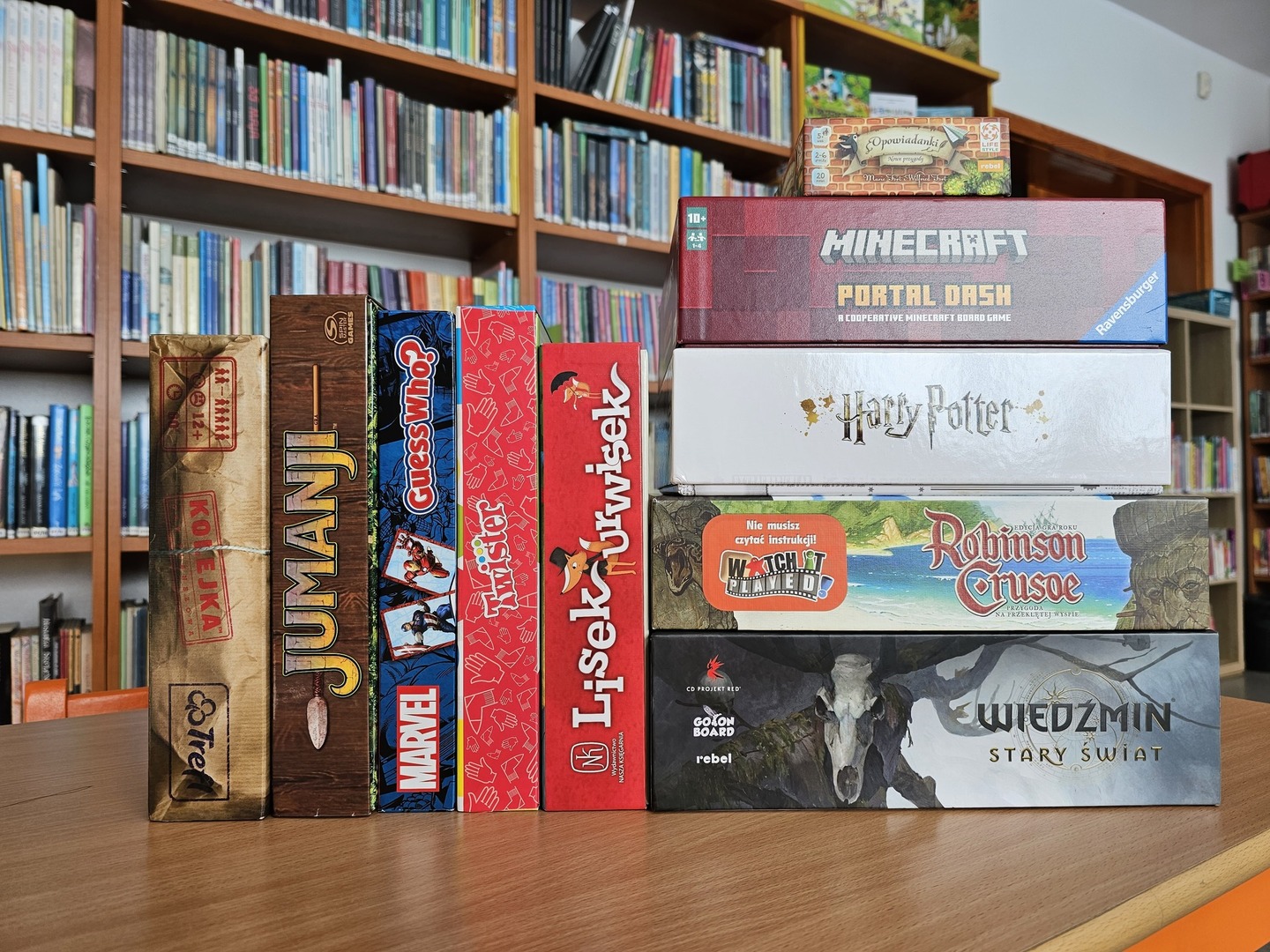 10 gier planszowych ustawionych jedna obok drugiej na brązowym stole