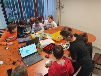 Grupa dzieci siedząca przy stole i składająca klocki lego
