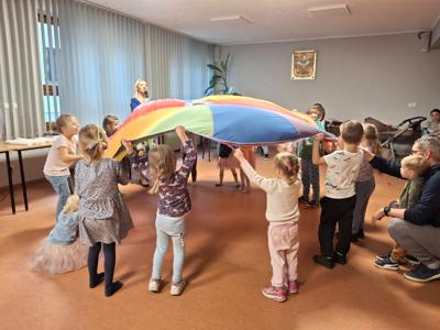 Dzieci bawiace się na sali dużą, kolorową chustą