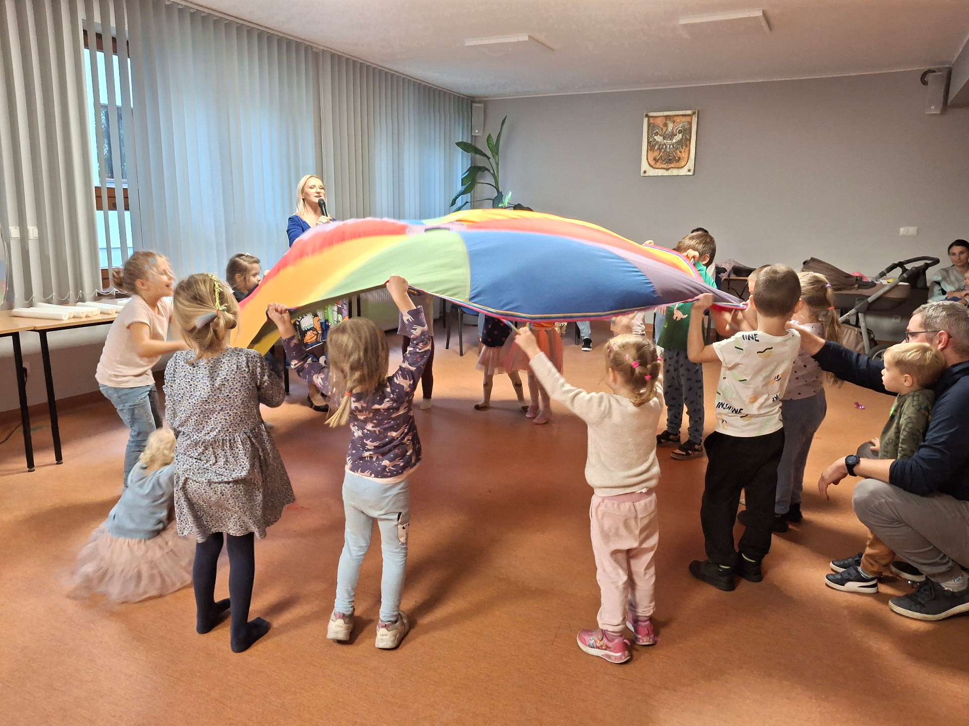 Dzieci bawiace się na sali dużą, kolorową chustą