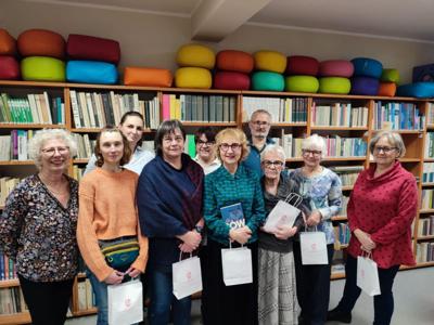 osoby dorosłe stojące przed regałami bibliotecznymi