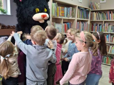 duzy czarny kot oraz dzieci przytulające się do niego