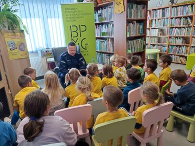 policjant czytający przedszkolakom w bibliotece