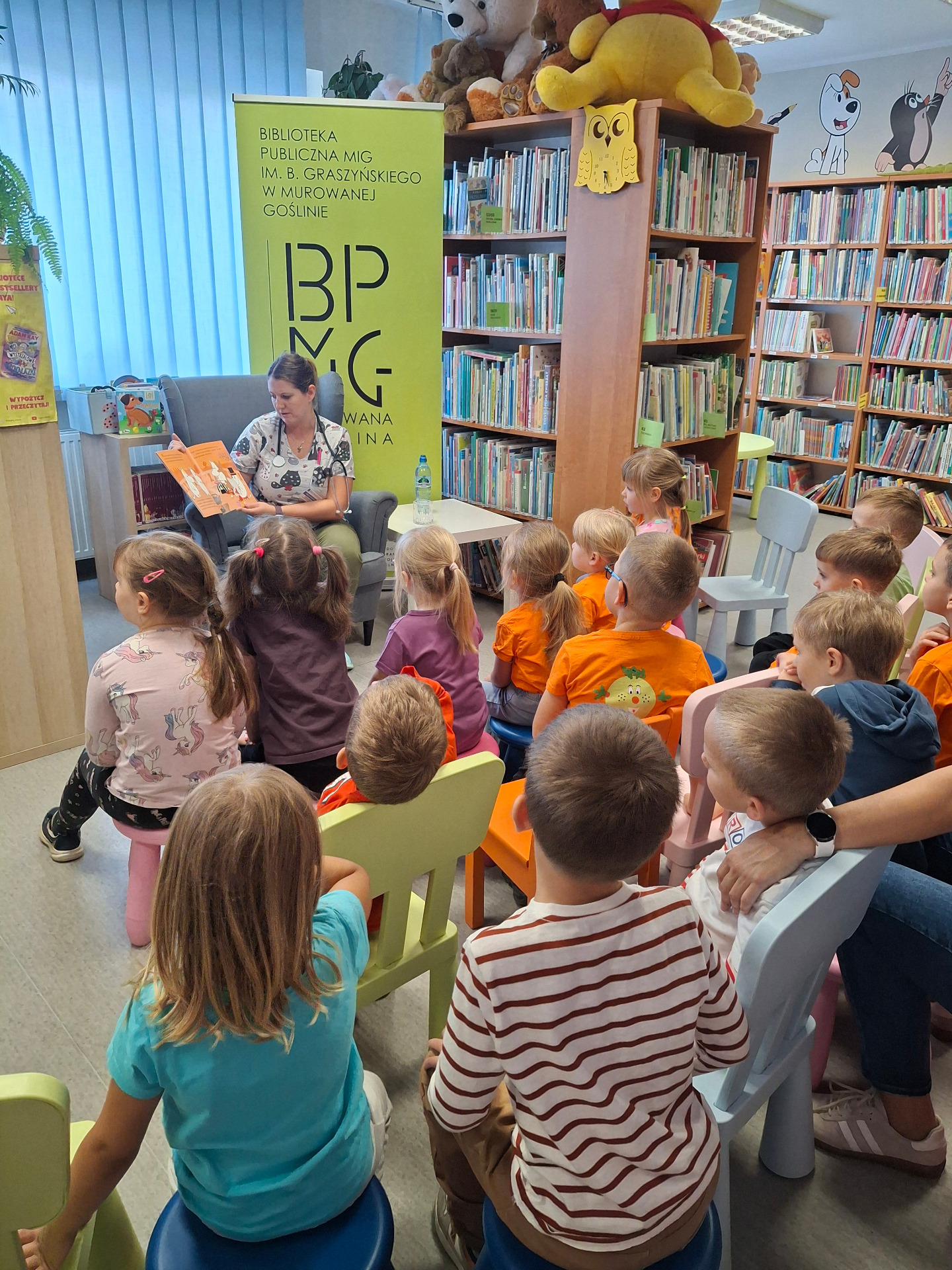 pielęgniarka czytająca przedszkolakom w bibliotece