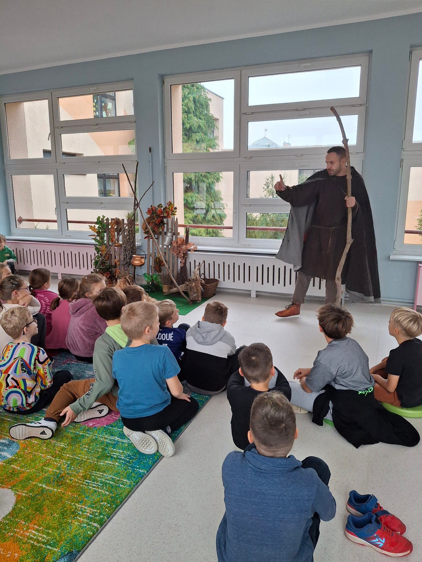 męzczyzna przebrany za pradawnego wędrowca opowiadający dzieciom siedzącym na dywanie legendy