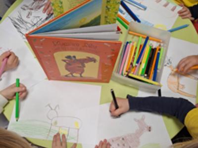 ręce dzieci rysujące postac z okładki ksiązki 