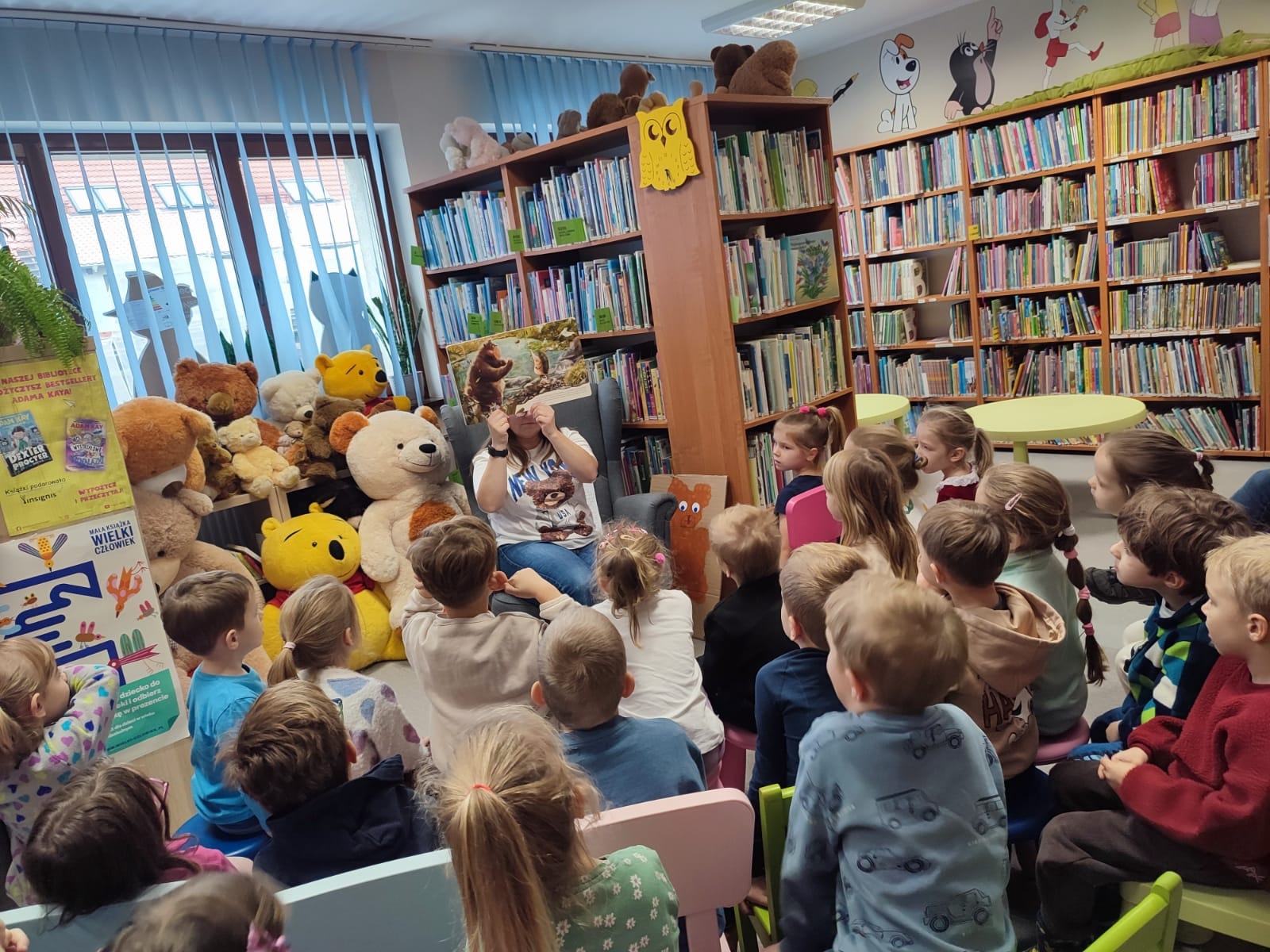 grupa dzieci siedząca w bibliotece