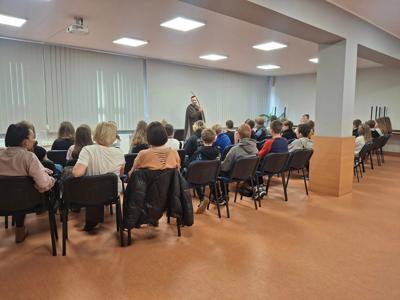 zgromadzeni ludzie siedzący na krzesłach  przodem do prowadzącego