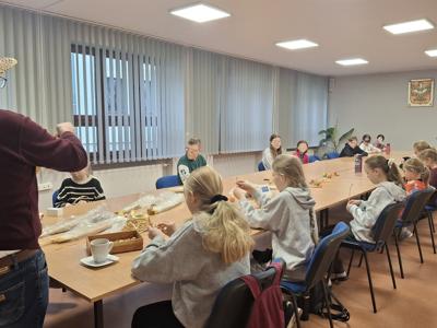 dzieci siedzące przy dużym stole, warsztaty wyplatania słomki