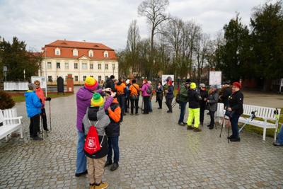 Grupa ludzi stoi przed Pałacem Książęcym, w tle budynek sądu w Żaganiu.