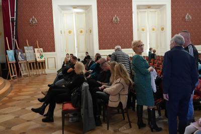 Sala Kryształowa w Pałacu Książęcym w Żaganiu - przed sceną stoją obrazy na sztalugach, ludzie siedzą przed sceną na krzesłach.