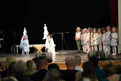 Grupa dziecięca przedstawiająca jasełka na scenie : dziewczynka wraz z chłopczykiem siedzą przy żłobku.