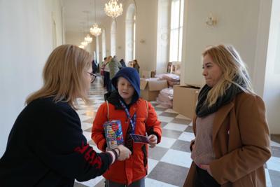 Dziecięcy wolontariusz WOŚP podaje paniom swój identyfikator.