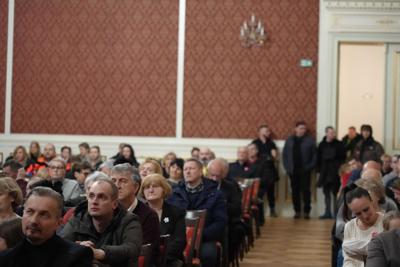 Siedząca publiczność ogląda występy. W drzwiach stoi również oglądająca grupa ludzi.