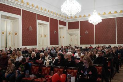 Publiczność ogląda występy. Nad nią majestatyczne żyrandole.