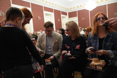 Osoby siedzące na publiczności. Przed nimi chłopiec z puszką na datki WOŚP.