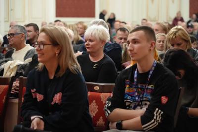 Publiczność oglądająca występy. Na pierwszym planie wolontariusz WOŚP siedzący wśród widowni.