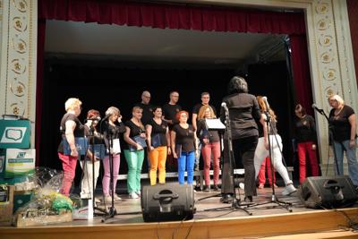 Grupa ludzi na scenie, występ chóru.