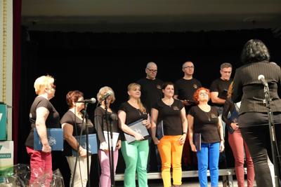 Grupa ludzi na scenie, występ chóru.