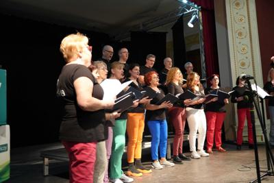 Grupa ludzi na scenie, występ chóru.