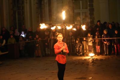 Jest ciemno, dziewczyna występuje z ogniem przed publicznością.
