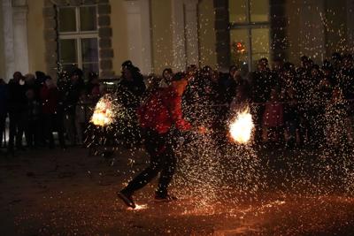 Jest ciemno, pan występuje z ogniem, w tle publiczność.