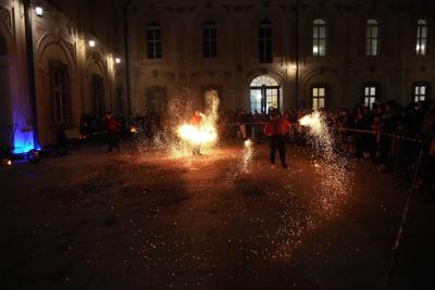 Jest ciemno, dwie osoby występują z ogniem, w tle publiczność.