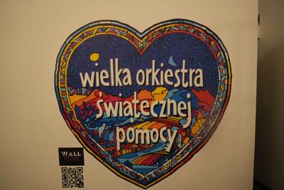 Kolorowe serduszko WOŚP nadrukowane na ścianie.