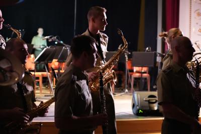Grupa artystów gra na instrumentach przed sceną.