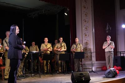 Orkiestra wojskowa stoi na scenie.