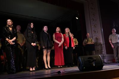 Artyści i orkiestra wojskowa na scenie.